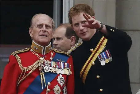  ?? Ap FiLE ?? CLOSE RELATIONS: Prince Harry talks with his grandfathe­r, Prince Philip, during a 2014 appearance on the balcony at Buckingham Palace. Philip, 99, the husband of Queen Elizabeth II for more than 63 years, died Friday. Below, the queen and Philip are joined by, from left, Princes Charles, William and Harry in 2004.