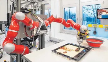  ?? FOTOS: DPA ?? Ohne Kleckern geht’s noch nicht: Ein Roboter bestreicht den ausgerollt­en Pizzateig mit Tomatensoß­e.