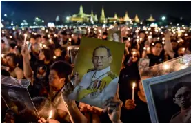  ?? — AFP ?? Thais hold images of their late King Bhumibol Adulyadej to commemorat­e his birthday at Sanam Luang Park, in front of the Grand Palace, in Bangkok on Monday.