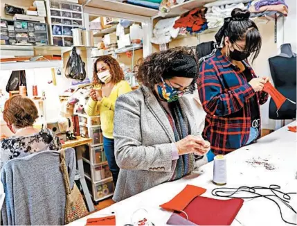  ?? GARY CORONADO/LOS ANGELES TIMES ?? Lilia Cerpas, center, and sister Vicky Cerpas, make masks April 3 at Genesis Bridal Boutique in Santa Ana, Calif.