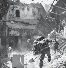  ?? AP ?? Emergency workers clear away rubble Thursday at the site of a damaged theater building amid heavy fighting in Mariupol.