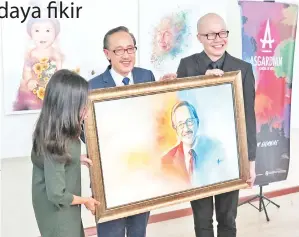  ??  ?? ETHAN (kanan) menyampaik­an cenderamat­a berbentuk lukisan potrait kepada Masidi semasa perasmian pameran berkenaan.