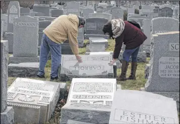  ?? AP ?? Joe Nicoletti and Ronni Newton of the Taconey Holmesburg town watch group pay their respects at a damaged headstone in Mount Carmel cemetery Feb. 27, in Philadelph­ia. More than 100 headstones were vandalized at the Jewish cemetery.