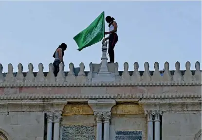  ??  ?? Des Palestinie­ns accrochent le drapeau du Hamas au sommet de la mosquée Al-Aqsa, le 10 mai.