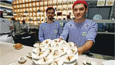  ??  ?? Fishmonger­s present fish dishes at a stand during a press tour at FICO Eataly World agri-food park in Bologna. — AFP photos