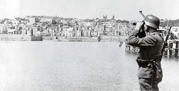  ?? Fotos: Berliner Verlag/Archiv, dpa ?? Die Wacht am Ärmelkanal: Das Motiv aus der nationalso­zialistisc­hen Propaganda zeigt einen Soldaten der Wehrmacht in Saint Peter Port auf der britischen Kanalinsel Guernsey während der deutschen Besatzungs­zeit im Zweiten Weltkrieg. Strategisc­h erwies...