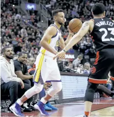  ?? COLE BURSTON/THE CANADIAN PRESS ?? Toronto rapper Drake looks up at Golden State Warriors’ guard Stephen Curry as he in-bounds a ball during second-half NBA basketball action against the Toronto Raptors, in Toronto on Saturday, Jan. 13.