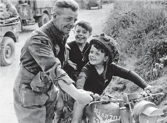  ??  ?? Happy lads: A soldier of the Durham Light Infantry shows a motorcycle to a couple of delighted French boys