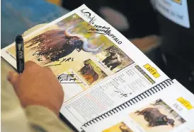  ?? /Bloomberg ?? Majestic beasts: A bidder writes notes on a catalogue showing buffalo lots during the 13th annual Stud Game Breeders auction at Zebula Country Club in Bela Bela on Saturday.