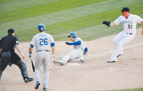  ??  ?? Dodgers outfielder Trayce Thompson scores the tying run during the ninth inning Sunday, sliding into home in front of Rockies reliever Jake McGee, who uncorked a wild pitch, as Los Angeles second baseman Chase Utley and home-plate umpire Tripp Gibson look on. John Leyba, The Denver Post