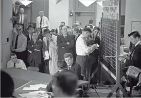  ?? MILWAUKEE JOURNAL ?? Sen. John F. Kennedy, center, is interviewe­d by NBC reporter Sander Vanocur in The MIlwaukee Journal newsroom on April 5, 1960, the night of the Wisconsin primary. Kennedy's chief rival, Sen. Hubert Humphrey, is seen standing behind Kennedy with his arms folded. At right, votes are tallied on a chalkboard while a member of the TV crew holds a boom mic to pick up the interview. This photo was published in the April 6, 1960, Milwaukee Journal.