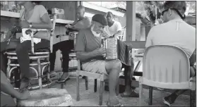  ??  ?? Pompey Johnson breaks out his accordion at Sunshine, a restaurant in New Bight, Cat Island, Bahamas, while a local boy plays a goat-skin drum and tourists look on.