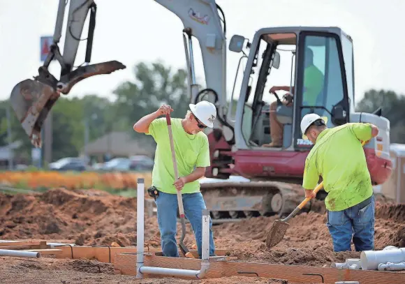  ??  ?? Jimmy Ivy, left, and J.C. Hall work on the foundation of a new Best Western being built off Interstate 55 in Marion, Arkansas. The hotel is part of a larger planned mixed-use developmen­t in its early stages called Angelo’s Grove that stalled during the...