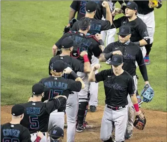  ?? Mitchell Leff Getty Images ?? THE MIAMI MARLINS celebrated their opening-day win but their home opener was canceled following 13 positive coronaviru­s tests, a foreboding sign for the sport that outweighs the joy it brings.