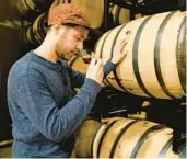  ?? JULIO CORTEZ/AP ?? Eli Breitburg-Smith, head distiller and co-owner of Baltimore Spirits Company, checks the quality of rye whiskey from a barrel Wednesday in Baltimore.