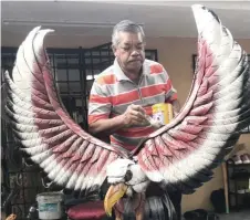  ??  ?? Zezali puts some final touches on an eagle arch made from used tyres. — Bernama photos