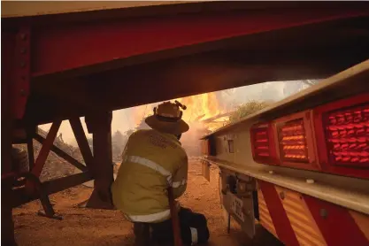  ?? FOTO: EVAN COLLIS/TT-AP-DFES ?? ■ En brandman söker skydd under en brandbil i släcknings­arbetet vid branden utanför Perth.