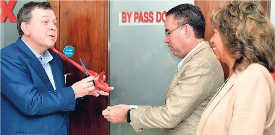  ?? FILE ?? Daryl Vaz (centre), minister without portfolio in the Ministry of Economic Growth and Job Creation (centre), IBEX CEO Bob Dechant, and Jampro President Diane Edwards at the ribboncutt­ing ceremony for Ibex’s new downtown Kingston office on January 17.