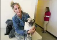  ?? RICHARD VOGEL — THE ASSOCIATED PRESS ?? In this Friday photo, evacuee Tracey Moechel sits with her dog Muggsy outside of an evacuation center set up at the Taft Charter High School gymnasium in Woodland Hills, section of Los Angeles. Moechel said Friday the center wouldn’t allow her dog to sleep inside.