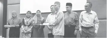  ??  ?? Rosey (third left) presents the assistance to one of the recipients, witnessed by Marini (second left), Abdul Aziz (fourth left) and others on stage.