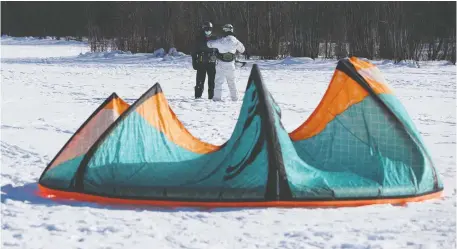  ?? TONY CALDWELL ?? Mike Morash, left, gets a kiteboardi­ng lesson from instructor Stanley Bocher near Andrew Hayden Park. Despite the pandemic, or because of it with the recent closure of ski hills, business is booming for snow-kite operators.
