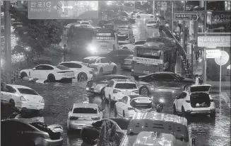  ?? YONHAP VIA REUTERS ?? Vehicles are left scattered in a flooded area of Seoul during torrential rainfall on Monday.