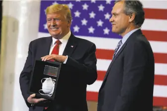  ?? Evan Vucci / Associated Press ?? President Trump receives a framed N95 mask Tuesday from Honeywell CEO Darius Adamczyk at the company’s mask plant in Phoenix. Trump has not been seen in public wearing a mask.