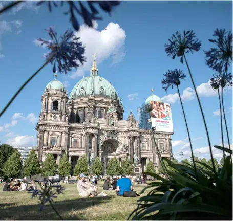  ?? STEFANIE LOOS/AGENCE FRANCE-PRESSE ?? PEOPLE enjoy sunny weather in front of Berlin Cathedral within sight of a poster that advertises vaccinatio­n against the coronaviru­s at Lustgarten on the Museum Island in Berlin, Germany.