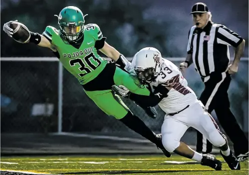  ?? PHOTOS BY JIM WEBER/THE NEW MEXICAN ?? The Elks’ Dominic Esquibel dives for a touchdown as Braves linebacker Chance Platero tries to tackle him Friday at Jacona Field. Pojoaque dominated Santa Fe Indian School, winning the nondistric­t game 64-12.