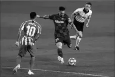  ?? ASSOCIATED PRESS ?? BARCELONA’S LIONEL MESSI (center) kicks the ball in front of Atletico Madrid’s Angel Correa during the Spanish La Liga soccer match between FC Barcelona and Atletico Madrid at the Camp Nou stadium in Barcelona, Spain, Tuesday.