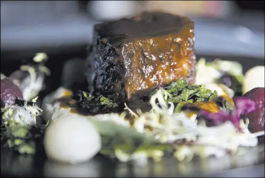  ?? Erik Verduzco Las Vegas Review-Journal @Erik_Verduzco ?? Slowly braised short ribs at The Black Sheep are served with creamy polenta, poached pears and sauteed turnip greens.