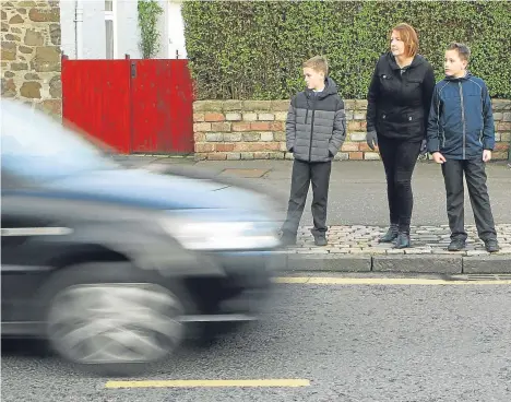  ??  ?? Angela with her children, Duncan, eight, and Alastair, 10, waiting to cross Forthill Road at the junction with Balgillo Road.