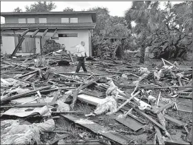  ?? AP/Orlando Sentinel/RED HUBER ?? Palm Bay, Fla., officer Dustin Terkoski walks over debris from a two-story home at Palm Point Subdivisio­n on Sunday in Brevard County, Fla., after a tornado touched down.