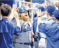  ?? AP PHOTO ?? Los Angeles Dodgers’ Justin Turner, center, celebrates with teammates after hitting a home run during the first inning of a baseball game against the Miami Marlins Sunday in Miami.