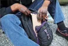  ?? Jessie Wardarski/Post-Gazette ?? C.J. Brown, 25, originally of East Liberty, puts his sign away in his backpack as he gets ready to leave the street corner with a case worker, Downtown. The primary winter shelter for homeless persons Downtown, at Smithfield United Church of Christ, is in jeopardy this season because of safety concerns.