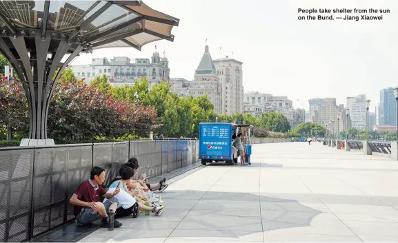  ??  ?? People take shelter from the sun on the Bund. — Jiang Xiaowei