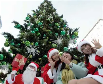  ?? PICTURE: AP ?? RIGHT STUFF: Shopping mall employees dressed as Santa Claus pose with a visitor under a Christmas tree, at the start of their special event to promote business in coincidenc­e with the upcoming yuletide season in Seoul, South Korea.