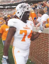  ?? STAFF FILE PHOTO BY DAN HENRY ?? Dontavius Blair, left, high-fives fans at the conclusion of the Orange & White Game in Knoxville in 2015. Center Ray Raulerson, right, and quarterbac­k Quinten Dormady practice snapping on April 16. Blair and Raulerson have decided to leave the...