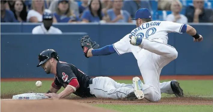  ?? Tom Szczerbows­ki/ Gett y Images ?? Cleveland’s Jason Kipnisreac­hes third base on a fielder’s choice in the first inning as Josh Donaldson of the Toronto Blue Jays cannot hold on to the ball Monday. The Indians won 4-2.