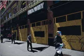  ?? BEN MARGOT — THE ASSOCIATED PRESS ?? Masked people walk past a boarded-up Old Navy clothing store Wednesday in San Francisco.