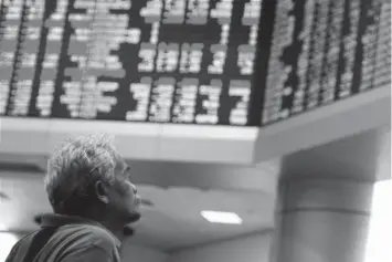  ?? ASSOCIATED PRESS ?? Investor sits at private stock trading boards at a private stock market gallery in Kuala Lumpur, Malaysia. Asian shares are mostly lower after Trump agreed with the EU to hold off on new tariffs.