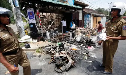  ?? Photograph: MA Pushpa Kumara/EPA ?? Sri Lankan policemen examine the remains of a business in Digana, Sri Lanka, after violence against Muslims last month.