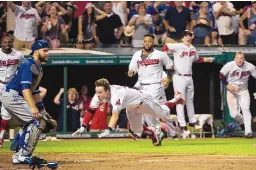  ?? AARON JOSEFCZYK/ASSOCIATED PRESS ?? Cleveland’s Tyler Naquin, center, dives for home plate for a game-winning inside-the-park homer in the ninth against Toronto on Friday night. Jays catcher Russell Martin is at left.