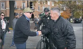  ?? MARYLAND GOV PICS/FLICKR ?? Gov. Larry Hogan gives a challenge medal to Easton Police Lt. George Paugh during the 50th Waterfowl Festival on Sunday, Nov. 14, in downtown Easton. On bicycle patrol in the background is 1st Sgt. Eric Kellner.