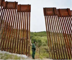  ?? AP PHOTO/MATT YORK ?? U.S. Border Patrol agent Jesus Vasavilbas­o looks into Mexico Thursday at a breach in the 30-foot-high border wall where a gate was never installed.