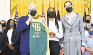  ?? AP ?? President Biden receives Seattle Storm jersey from players Jewell Loyd (c.) and Breanna Stewart (r.) during ceremony in East Room of White House on Monday.