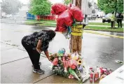  ?? GABRIELA BHASKAR / NYT ?? A woman leaves flowers at a makeshift memorial on Monday to the victims of Saturday’s mass shooting at Tops supermarke­t in Buffalo, N.Y.