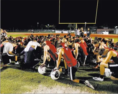  ?? Joe Skipper ?? The Associated Press Marjory Stoneman Douglas High School football players pray together as they begin practice for a new season just after midnight Monday in Parkland, Fla. The school was the scene of a shooting on Feb. 14 that killed 17.