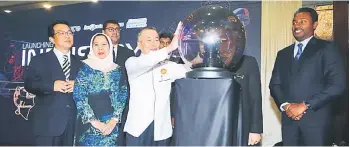  ?? — Photos by Muhammad Rais Sanusi ?? Naroden touches the crystal ball as the launch gimmick for the event, as Hallman (left), Rosey (second left) and others look on.