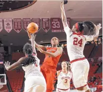  ?? GARY STEPIC/FOR THE JOURNAL ?? Lobo Alex Lapeyroler­ie drives toward the basket in the face of defensive pressure from OU’s LaNesia Williams, left, and Ijeoma Odimgbe (24).